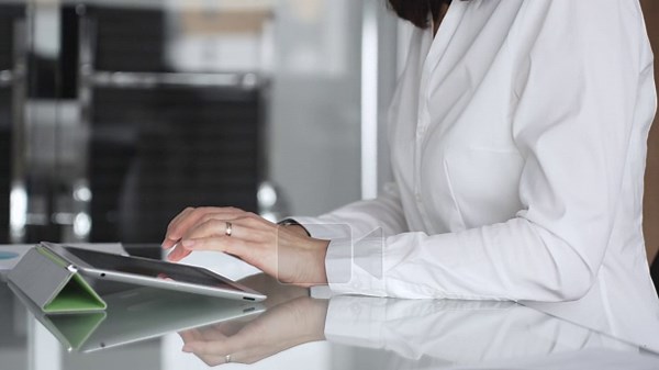 Businesswoman hands interacting with a digital tablet on a clean glass desk, performing tasks related to business operations, technology integration, and efficient workflow in a modern office Stock Video Footage - Alamy