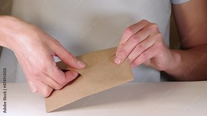 Female hands open a brown paper envelope and take out a letter, full hd close-up. Happy woman receiving handwritten letter