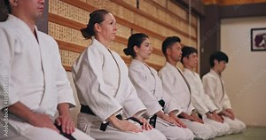 Dojo, students and respect with bow for martial arts, karate practice or greeting with honor in class. Group, people and etiquette with kneeling for learning combat, self defense or training in Japan