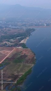 Vertical video of Drone footage of the southern part of Kampot, Cambodia. The camera is facing Kampot city and is descending heading away from the city over of the Prek Kampong river.