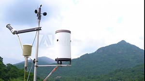 Meteorological weather station antenna with meteorology sensors, pale overcast cloudy sky and forest in background. Weather station for background.