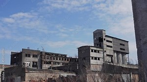 Buildings of an old ruined factory with broken windows. Brick houses, hangars, warehouses with burnt black walls.