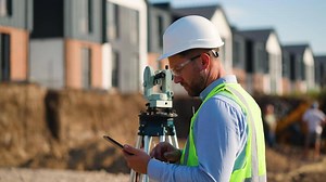 Surveyor engineer using theodolite and tablet on construction site