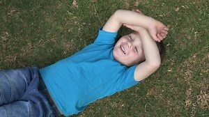 clip-10901219-cute-young-boy-lying-on-grass-laughing