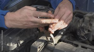 a male car mechanic removes a hose in a car, remove the clamp from the hose with pliers, disconnect the hose from the car engine