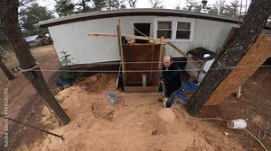 Man shoveling or moving pile of sand away from home made well to make space for new soil from the bottom of hole.