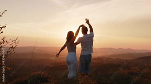 A young couple dancing at sunset. The sun's rays illuminate the boy and the girl.