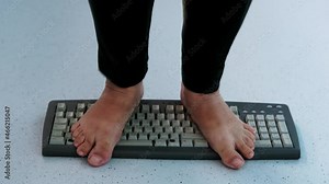 child stands, jumps, dances with his feet on computer keyboard, presses buttons, little vandal, bully plays with gadget, bullying concept, spoils technology until parents can see