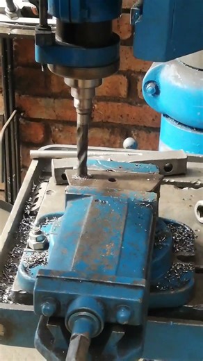 IN MANUFACTURING WORKSHOP USING ADJUSTABLE TABLE ON DRILLING MACHINE TO GET TO HEIGHT
