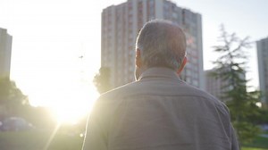 The old man is walking outdoors. Old man walking alone.