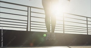 Woman athlete in skinny leggings jumps on jumping rope while sun shines. Young female includes jump rope routines into daily fitness regimen