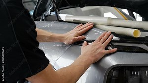 Close up of paint protection film installation on front bumper of modern luxury car. PPF is polyurethane film applied to car surface to protect the paint from stone chips, bug splatter, and abrasion.