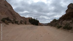 Desert dirt road driving past scenic rock formations with car mount in Southern California.