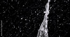 spray of water bursting from the bottom of the screen and water droplets fall down against the black background.