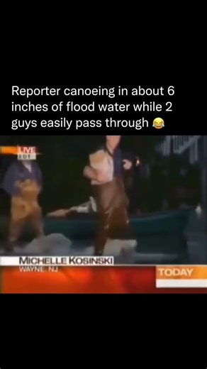 Reporter canoeing in a out 6 inches of flood water while 2 guys easily pass through