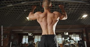 A male bodybuilder trains his chest muscles while working out on the simulator.