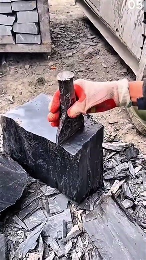 Person splitting slate rock using chisel and hammer
