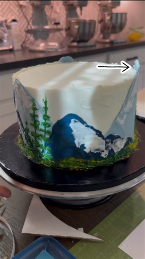 Sarah Norman on Instagram: "A beautiful buttercream mountain scene made easy by simply applying your buttercream first to a piece of wax paper and applying to the cake. Not only does it help to ensure the exact shape and size of the mountain that you're trying to create, but it creates a beautiful texture and allows you to easily layer at your mountains. Just make sure to freeze your cake after you apply your wax paper before you peel it off… This will give you that perfect crinkled texture from