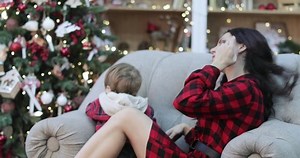 Mom and son on the couch in checkered clothes against the background of the Christmas tree