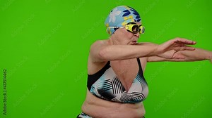 Mature woman traveler swimmer in swim goggles, dancing, showing swimming movements. Senior grandmother in swimsuit bra on chroma key background. Tourism, summer holiday vacation, trip to sea, pool