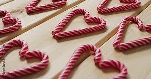 Video of red and white candy canes on wooden background