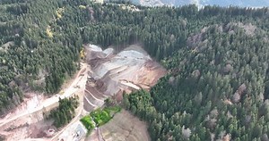 Industrial mine excavators are digging the soil in the construction site and loading trucks. Aerial drone top view.
