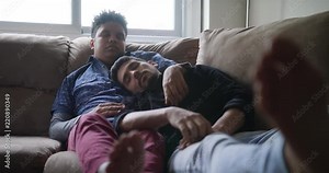 Young Gay Men Sleeping And Relaxing On Sofa At Home