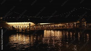footage of Golden Gate Ferry Terminal with people walking at night and the San Francisco Oakland Bay Bridge with lights in San Francisco California USA