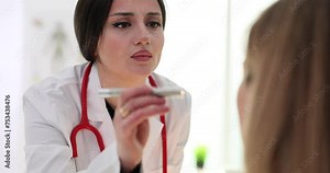 Female doctor examines pupils of patient using flashlight