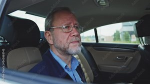 Caucasian tired elderly man sitting in back of car on motion. Wealthy old business person is driving to work. Portraits. Transportation. Lifestyle.