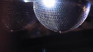 Disco ball rotates. Close-up. Mirror ball spinning and making club lasers indoors. Performance. The reflection of lights.