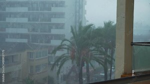 Stormy and rainy weather in Alcudia on Mallorca in Spain with Palm tree and hotels in the background.