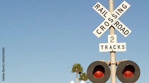Level crossing warning signal in USA. Crossbuck notice and red traffic light on rail road intersection in California. Railway transportation safety symbol. Caution sign about hazard and train track.