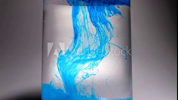 An exciting slow-motion video showing the scattering and swirling of a bright blue dye as it spreads in clear water, illustrating the dynamics of the liquid and the mixing of colors.