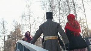 Russian folk - men in traditional costumes dance on the bridge