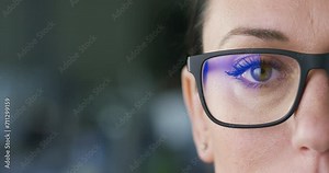 Super Close-up Frontal Shot on Female Green Eye: Beautiful Caucasian Brunette Woman Wearing Glasses Looking at Camera Against a Blurred Background. Concept: Vision, Optician, and Healthcare