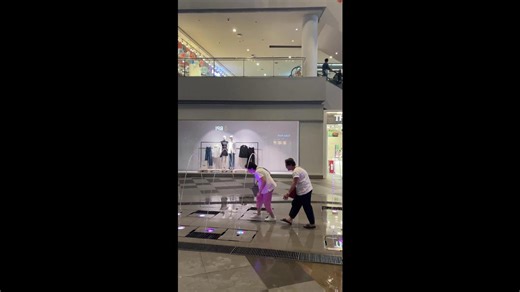 Grandmothers join little girl running through water fountain arches at mall