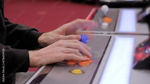 Close up side view: man gamer hands playing retro arcade machine game and pushing orange buttons. Gaming, 80s, hobby, vintage, technology, retro video game and leisure time concept