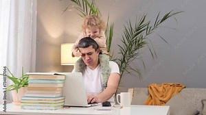Kid-friendly home office. Office technology for parenting. Laptop use in family life. Caucasian man working on laptop with baby daughter on his shoulders at home