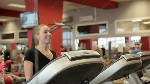 Running on a Treadmill. Close up. Three beautiful women train on a treadmill. Girls in the gym go on treadmill. Three sports girls on treadmill. Reflection in a mirror. The girl smiles on a treadmill