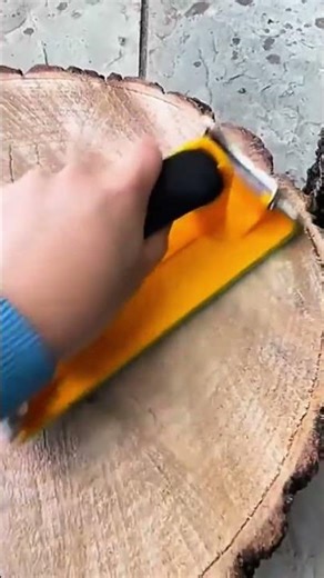 smoothing the rough surface of a large round log slice using hand sander tool to reveal the natural