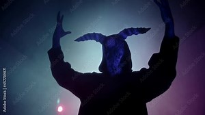 Demon with horns conjuring close-up. Silhouette of devil in darkness. Halloween, a traditional American holiday concept. Evil magician making rite or sacrifice during full moon, evil spirit, satan.