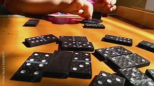 Teaching children to play dominoes game on a wooden background, domino principle, the child is playing.