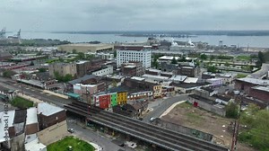Downtown Chester, Pennsylvania. Aerial establishing shot of crime-ridden suburb of Philadelphia. Kimberly Clark manufacturing plant and Delaware River in distance. SEPTA commuter train tracks.