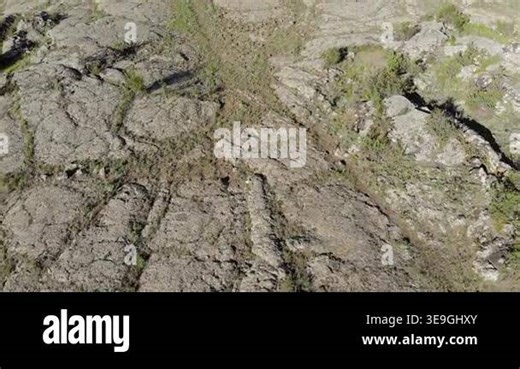 Drone aerial view shows frozen basalt lava plain with cracked rock textures plus badlands. Solidified magma forms igneous terrain across remote volcanic wilderness, barren relief. geology, landscape, frozen lava, basalt plain Stock Video Footage - Alamy
