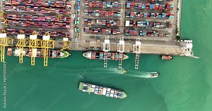 container ship and commercial port loading and unloading cargo from container ship import and export by crane for distributing goods by trailers transported 4k video top view Stock Video