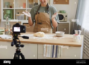 Young woman wearing apron standing at the kitchen and making dough for cake and shooting the video for content Stock Photo - Alamy
