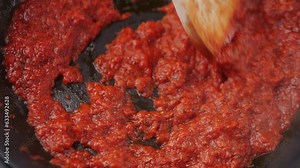 Classic homemade Italian tomato sauce with basil for pasta and pizza in the pan. Chef cooking traditional Italian food.