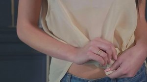 Crop footage of young teen girl is ties a knot on her shirt in slow motion. Youth culture concept.