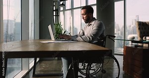 Man in wheelchair efficiently manages his tasks using laptop, search issue solution, learn new program, review documents, communicating through emails, analyze data, completing reports. Telecommuting